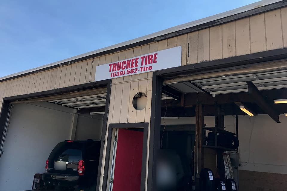 The old Truckee Tire shop: a white sign over two open bays and a red door, a black SUV on a lift in the left bay